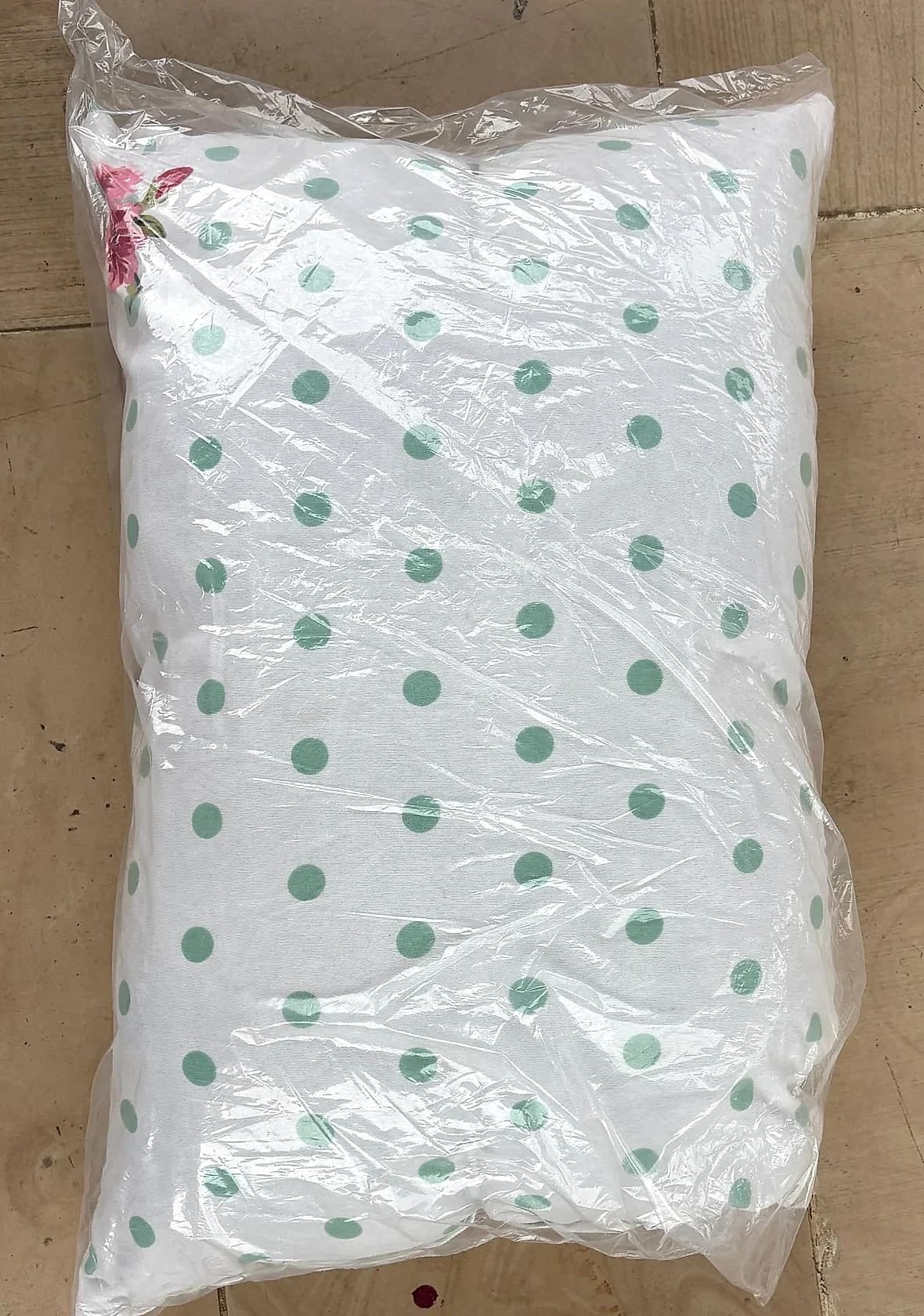 White and teal polka dot pillow sealed in retail packaging sleeve